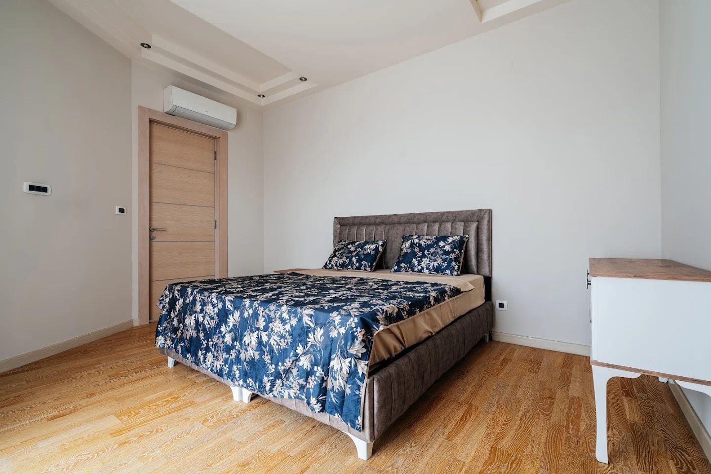 Bright bedroom with a double bed in a modern apartment in Budva, Montenegro: parquet flooring, air conditioning, stylish decor.