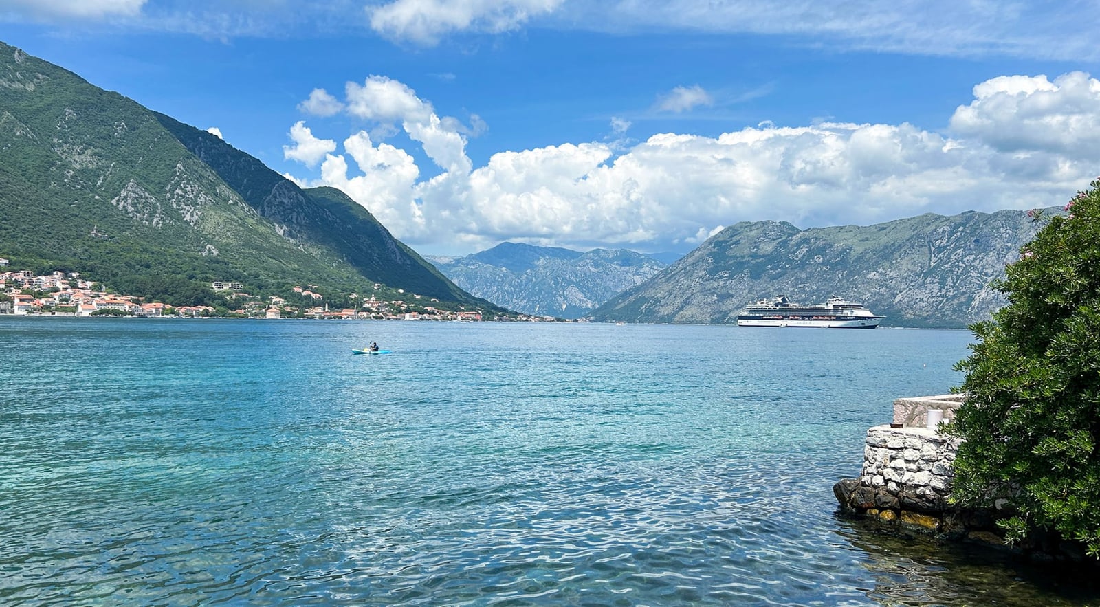 Panoramic view of Kotor Bay and the mountains from the villa shore in Dobrota, Montenegro: sea, cruise ship, and pier.