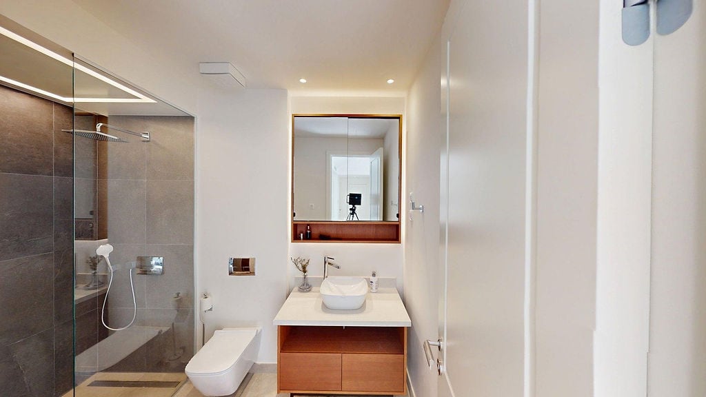 Modern bathroom in an apartment, Luštica, Montenegro: shower cabin, vanity unit with sink, and illuminated mirror.