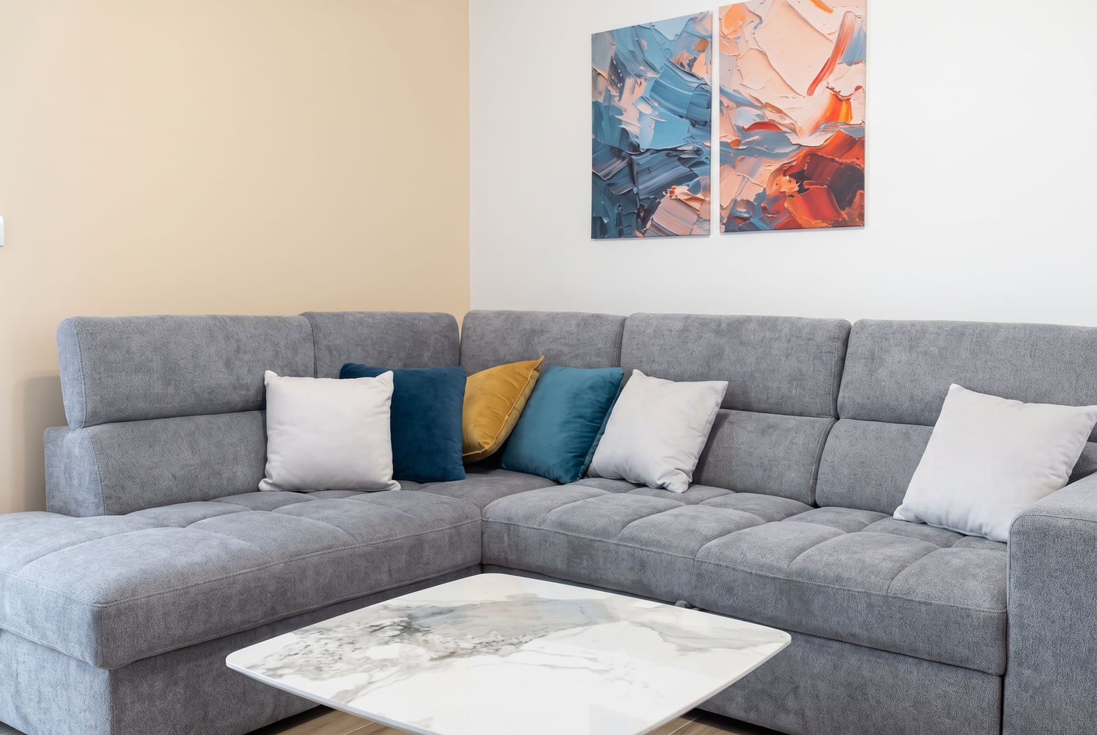 Corner gray sofa with pillows and a coffee table in the living room of an apartment in Bečići, Montenegro.