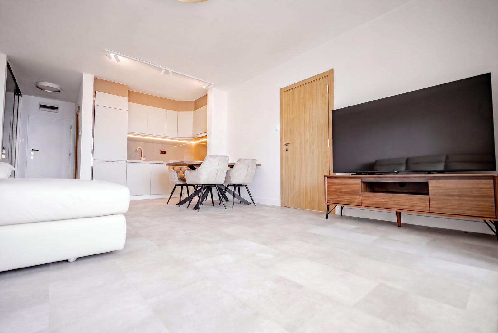 Modern living room with kitchen in an apartment in Sveti Stefan, Montenegro: light furniture, TV area, and dining set.