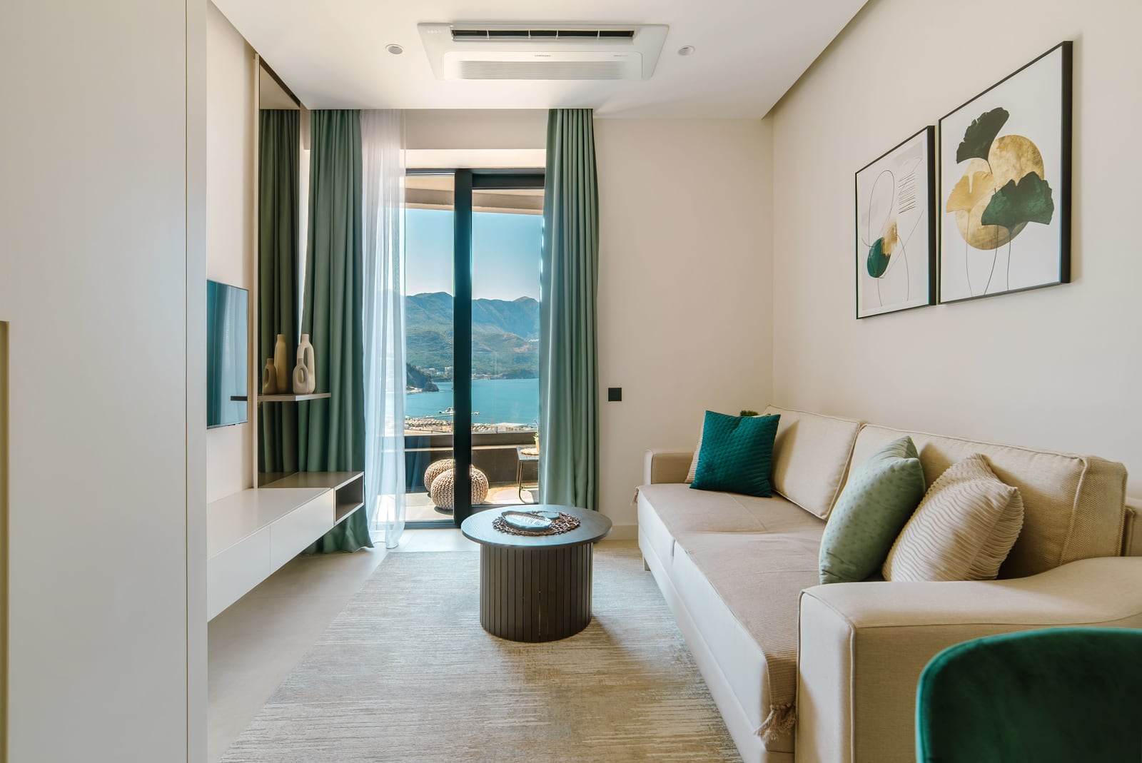 Modern living room in an apartment, Bečići, Montenegro: bright interior, sofa, sea and mountain views from panoramic windows.