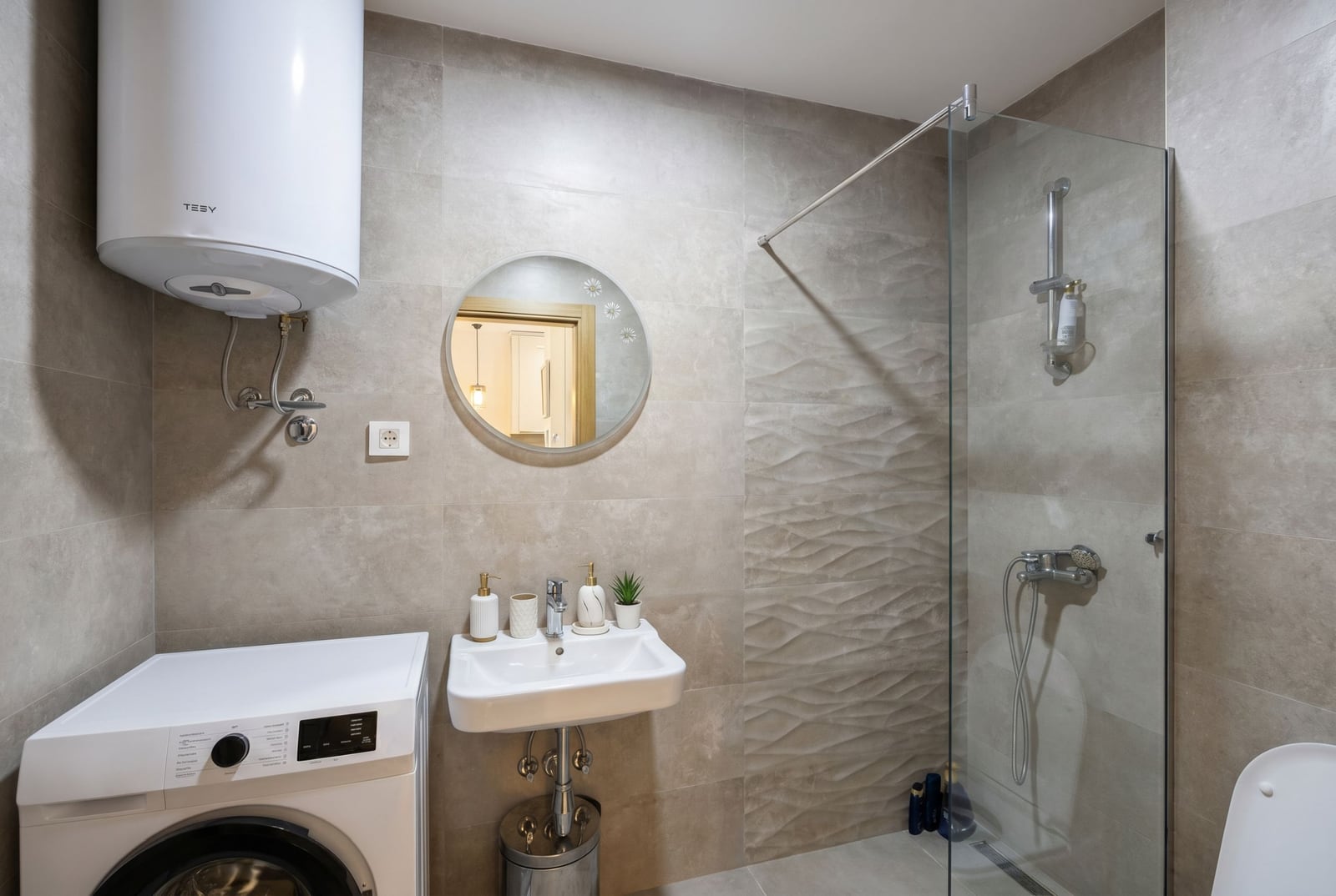 Modern bathroom in an apartment in Bečići, Montenegro: shower cabin, washing machine, and Tesy water heater.