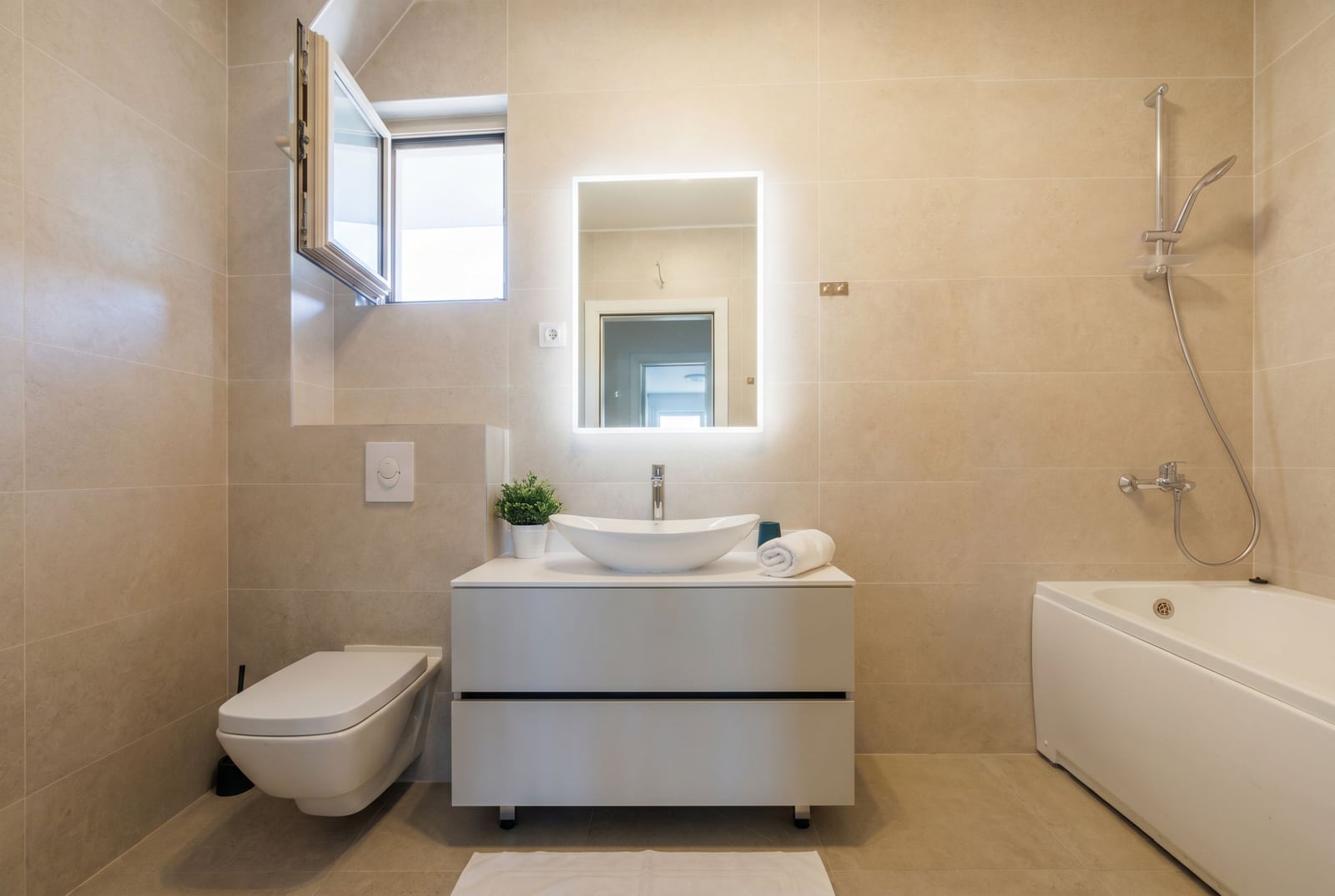 Modern bathroom in a penthouse, Bečići, Montenegro: white sanitary ware, vessel sink, and backlit mirror.