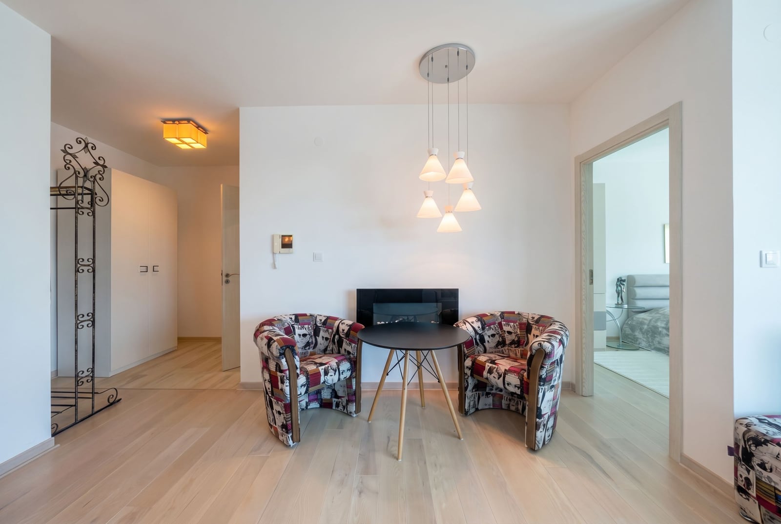 Living room with designer armchairs and a fireplace in an apartment in Bečići, Montenegro: modern interior with parquet flooring.