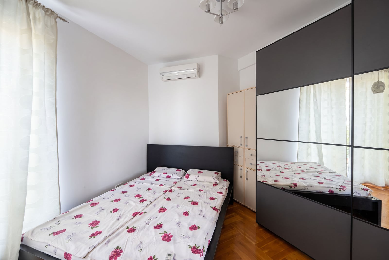 Bedroom with a double bed, large mirrored wardrobe, and air conditioning in an apartment in Bečići, Montenegro.