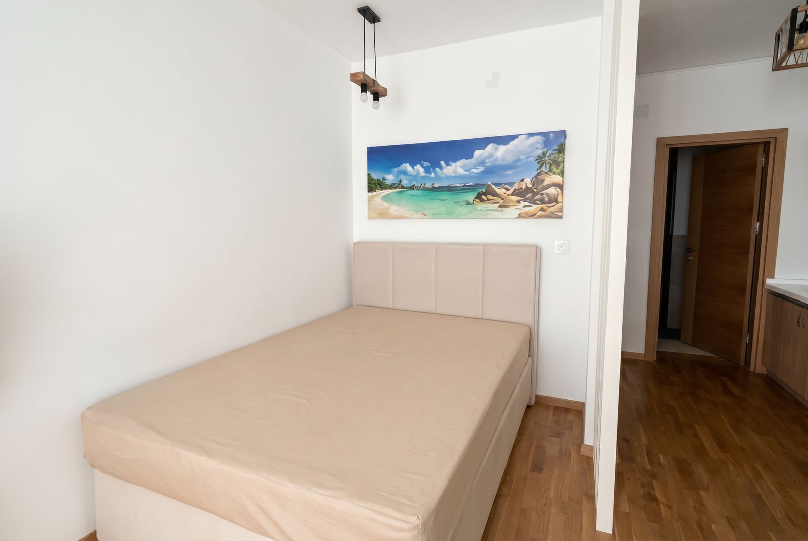 Cozy bedroom with a double bed in an apartment in Becici, Montenegro: modern interior, parquet flooring, and wall decor.