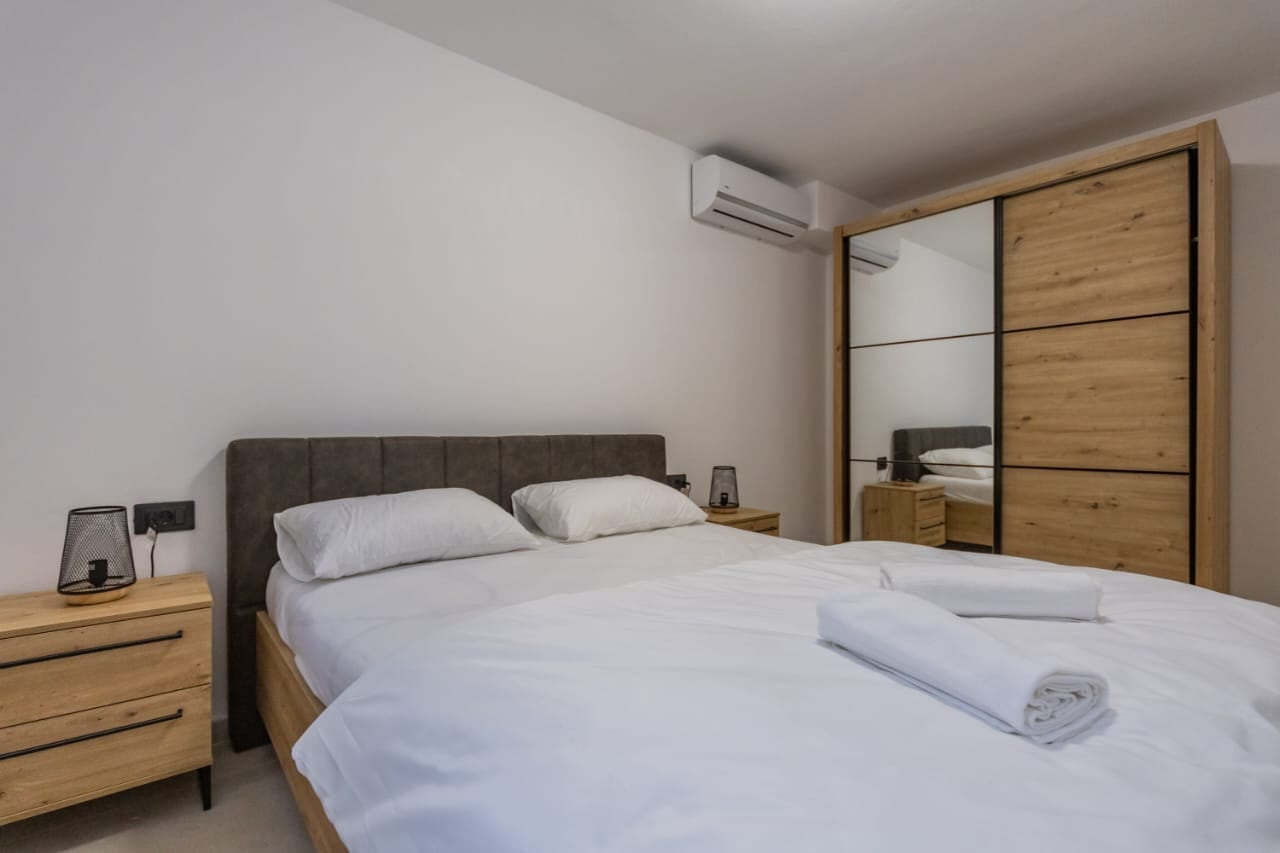 Modern bedroom with a double bed and a built-in wardrobe in a villa in Budva, Montenegro. Bright interior with wooden furniture.