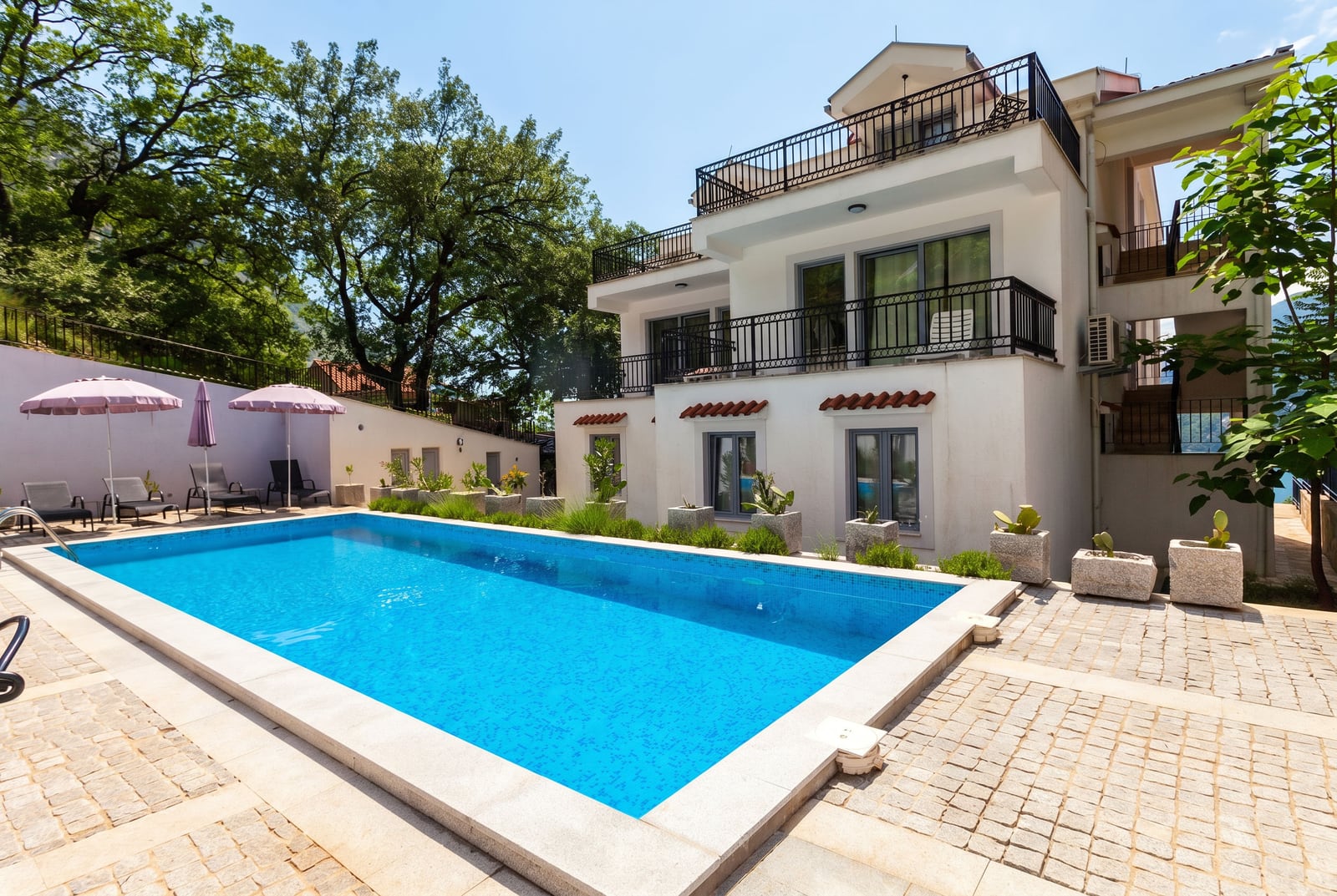 Two-story villa with a pool and lounge area in Risan, Montenegro: terrace with sun loungers and modern architecture.