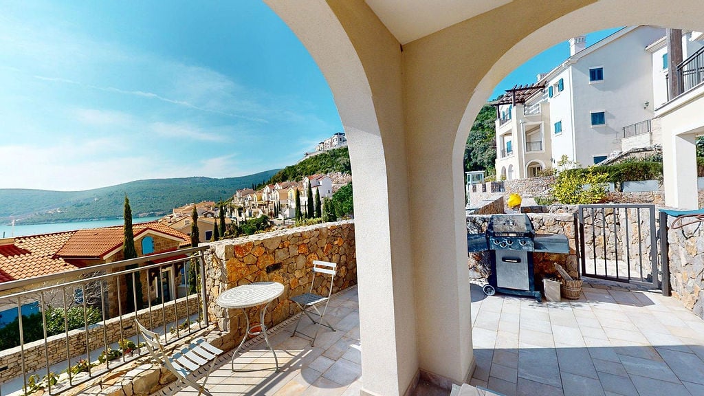 Terrace with grill and sea view in the Luštica residential complex, Montenegro: stone finish, lounge furniture.