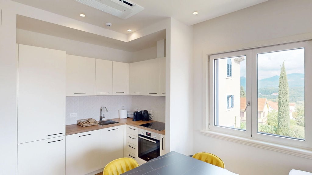 Modern white kitchen in an apartment in Luštica, Montenegro, with mountain views and built-in appliances.
