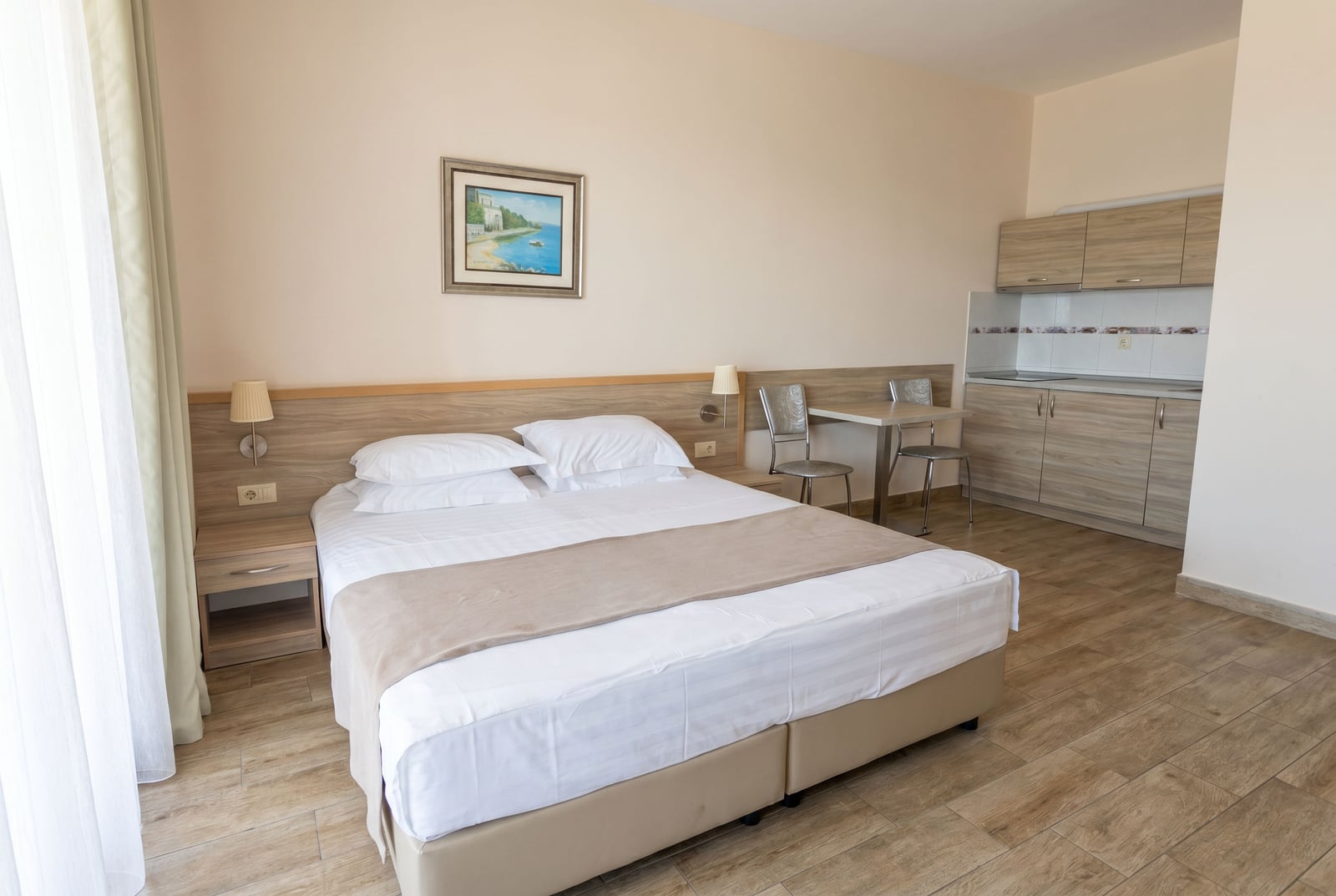 Bright bedroom with a double bed and a kitchenette in an apartment, Becici, Montenegro. Modern interior.