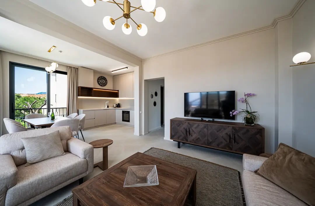 Modern living room with kitchen in a villa in Reževići, Montenegro: bright interior, designer furniture, and garden view.
