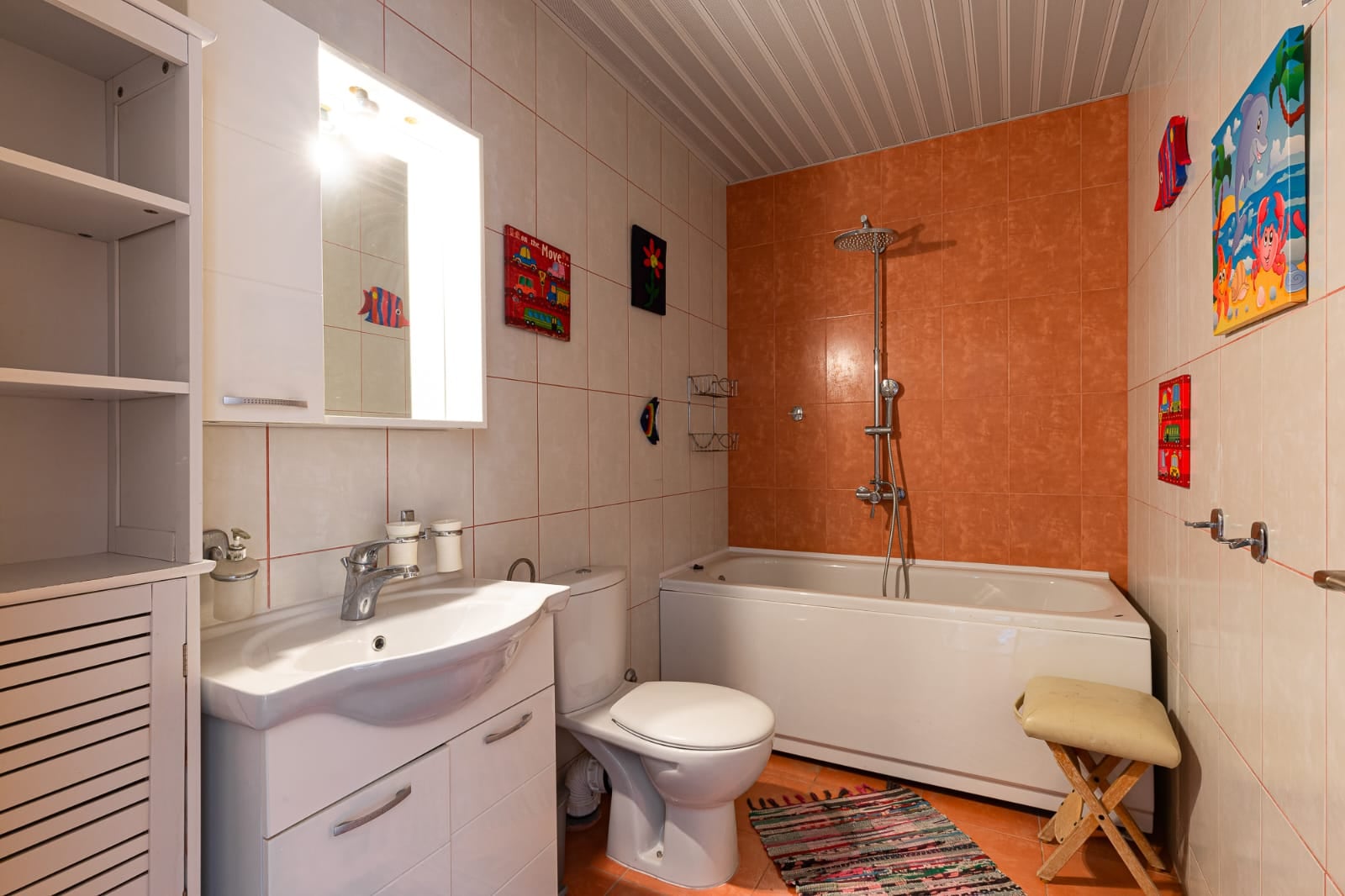 Bathroom with a walk-in shower and white furniture in a villa in Bečići, Montenegro: interior featuring orange tiles and decor.