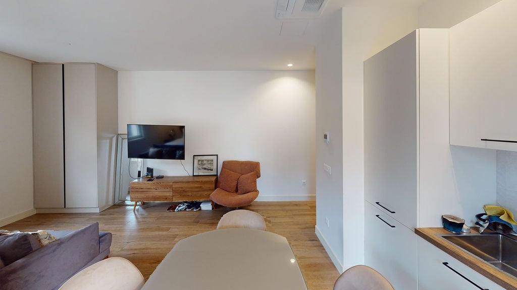 Modern living room with kitchen in an apartment, Luštica, Montenegro: light finishes, wooden floor, and cozy furniture.