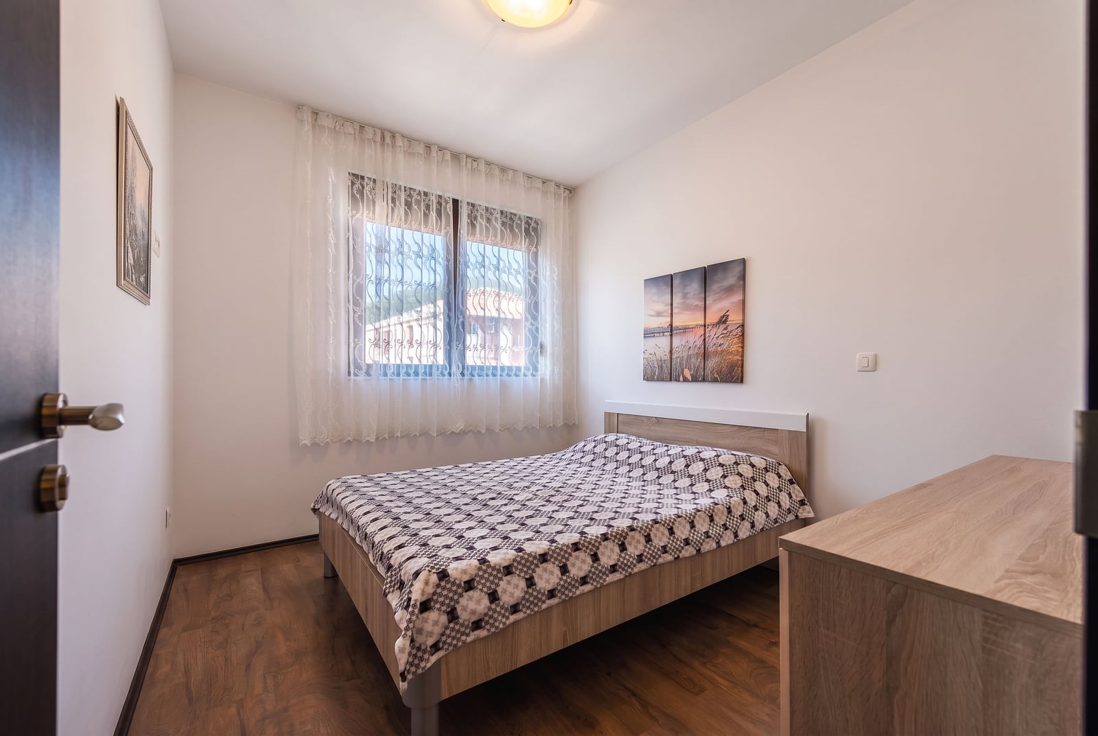 Cozy bedroom with a double bed in an apartment in Budva, Montenegro: light finishes, laminate flooring, and wall decor.