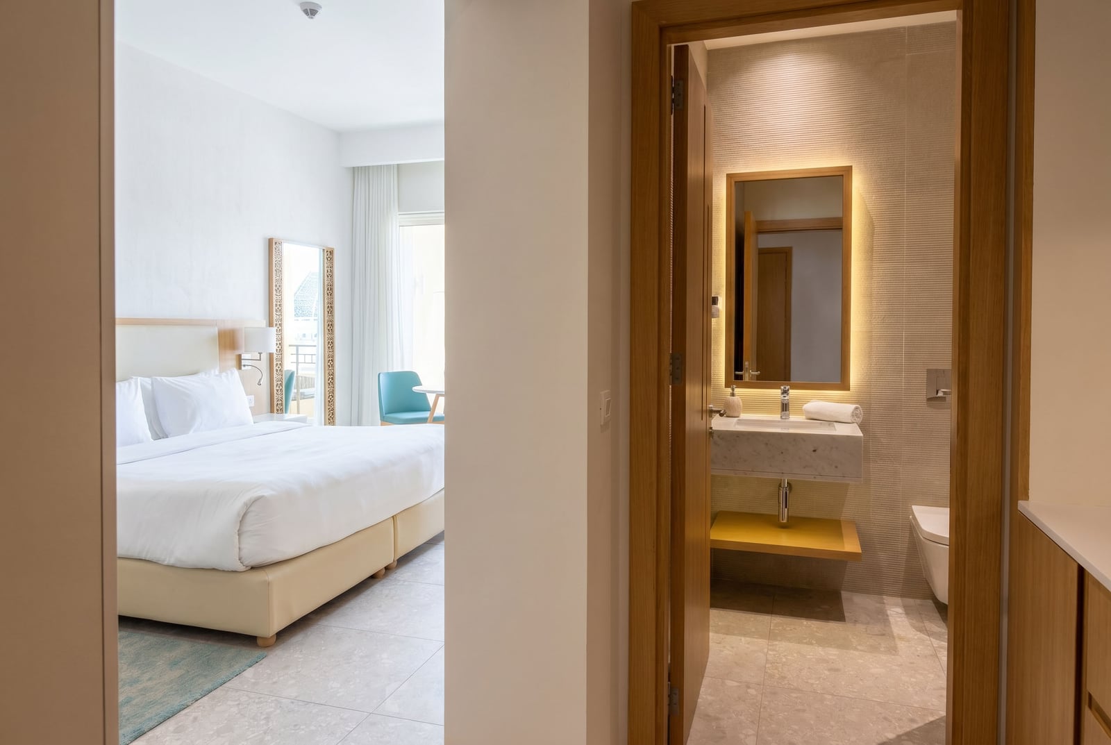 Modern bedroom and bathroom in a Lustica Bay apartment, Montenegro: bright interior, double bed.