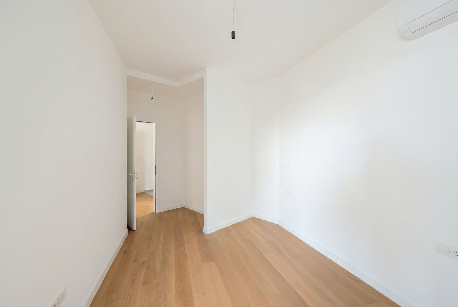 Bright bedroom with parquet flooring and air conditioning in a new apartment in Bečići, Montenegro. Modern interior finishes.