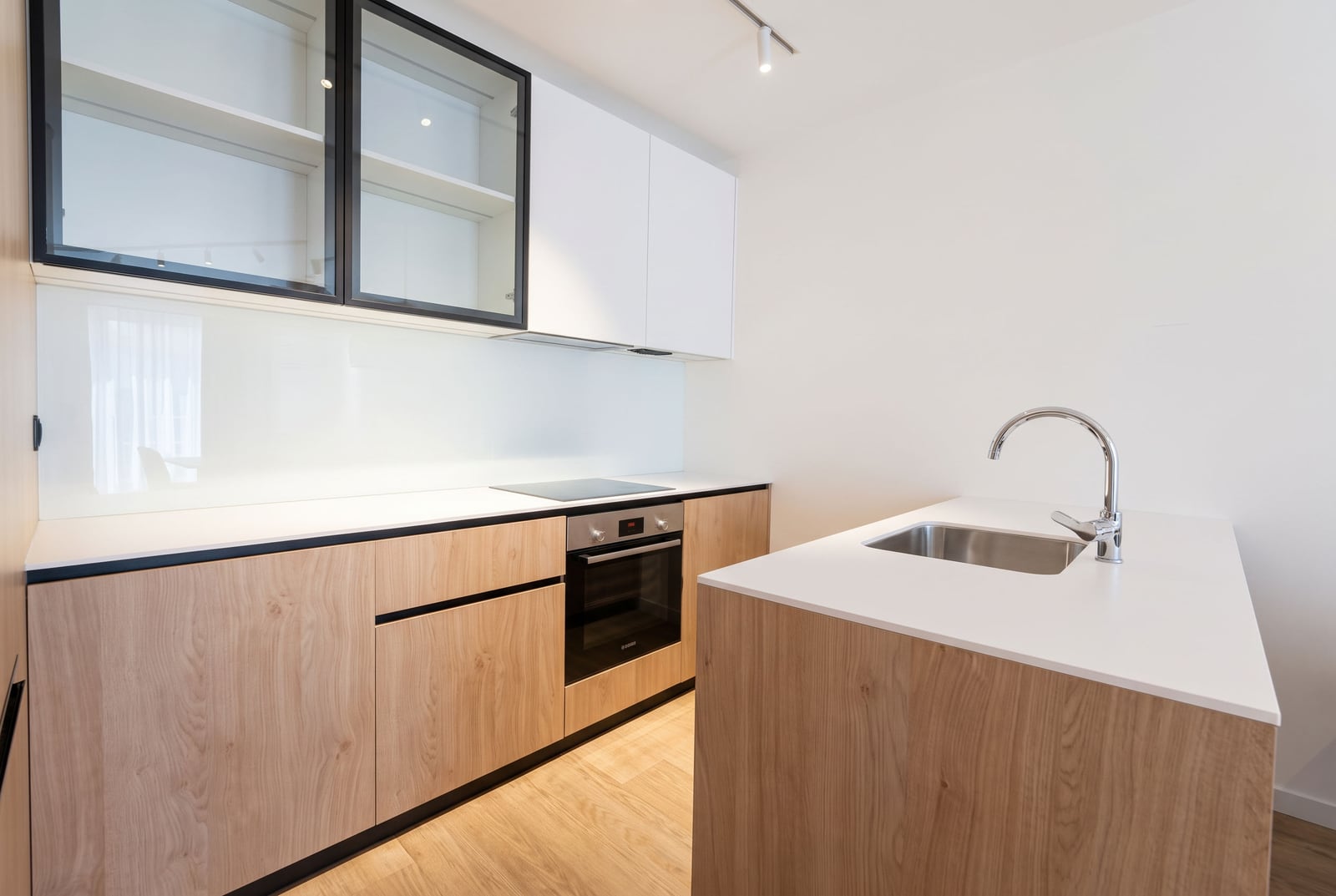 Modern kitchen with wood-look furniture, white facades, and an island in an apartment in Budva, Montenegro