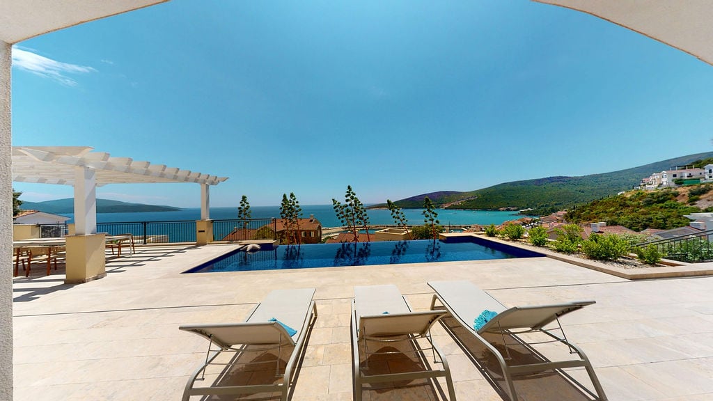 Terrace with an infinity pool, sun loungers, and sea view at the Luštica residential complex, Montenegro.
