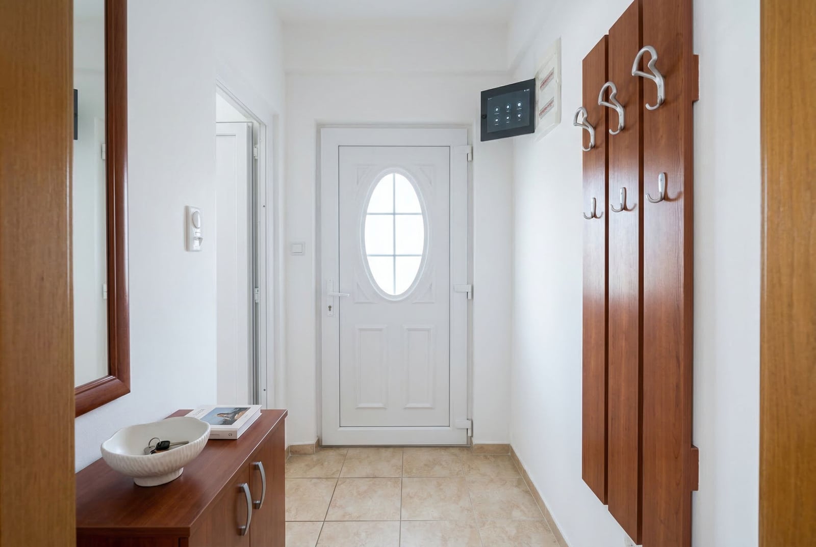 Bright hallway in an apartment, Budva, Montenegro: white front door, wooden coat rack and cabinet in a studio interior.