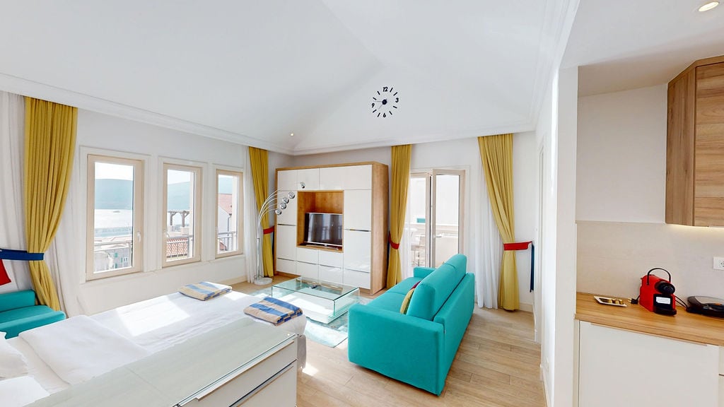 Bright living room with kitchen in Luštica apartments, Montenegro: modern furniture, sea view, and panoramic windows.