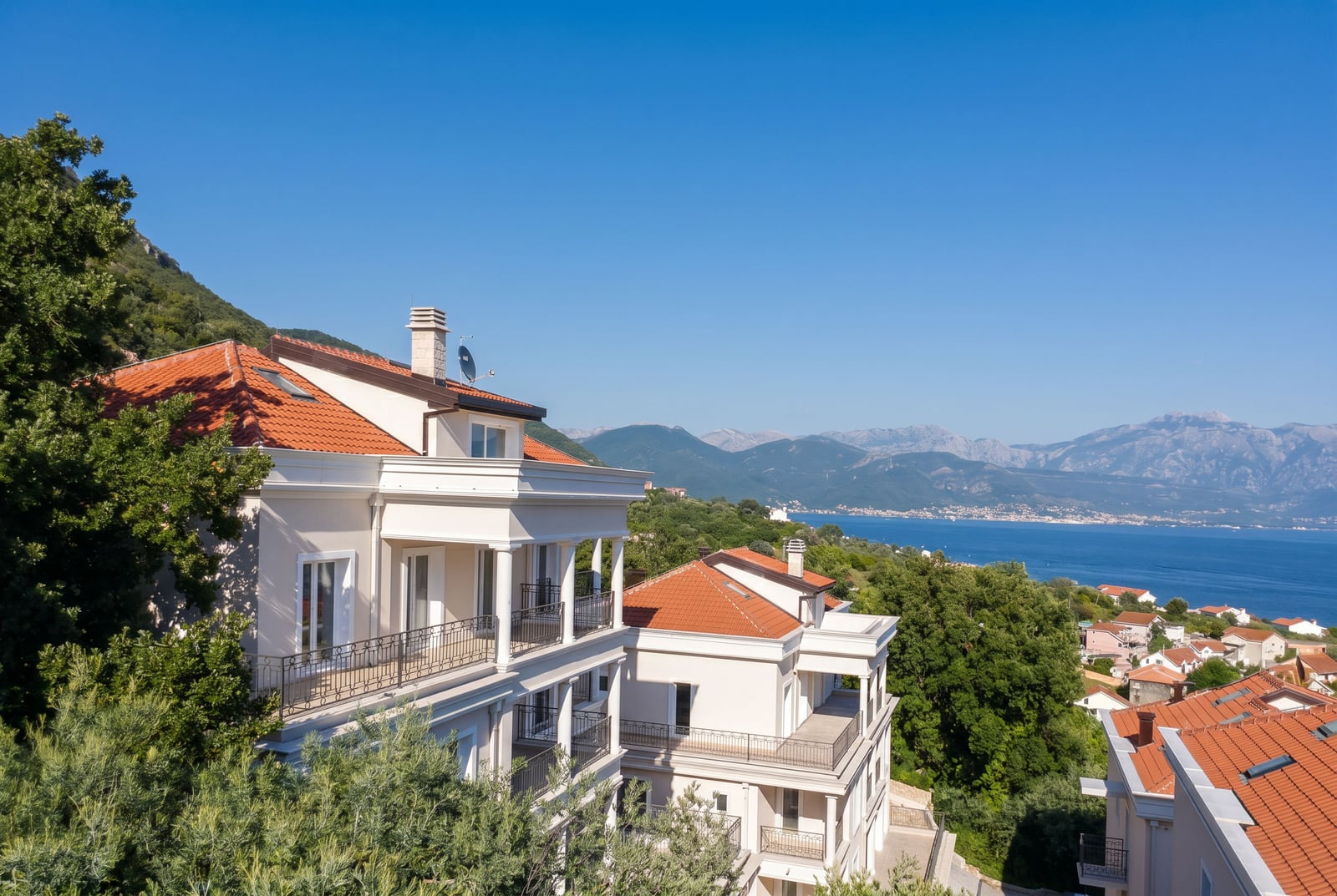 Residential complex in Kumbor, Montenegro: villas with terraces, tiled roofs, and panoramic views of the Adriatic Sea.