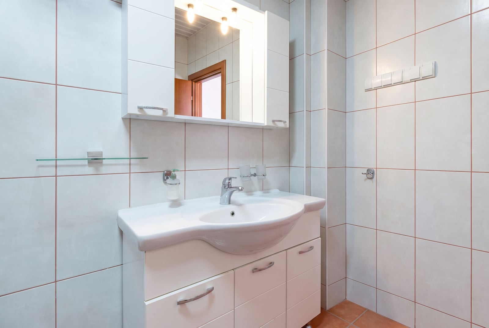 Bright bathroom with a white vanity and mirror in a villa in Bečići, Montenegro. Modern tile finishes.