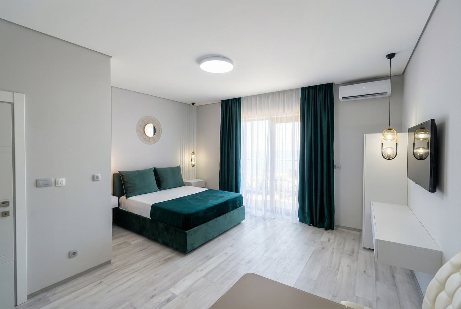 Modern bedroom with an emerald bed and access to the balcony in an apartment in Bečići, Montenegro.