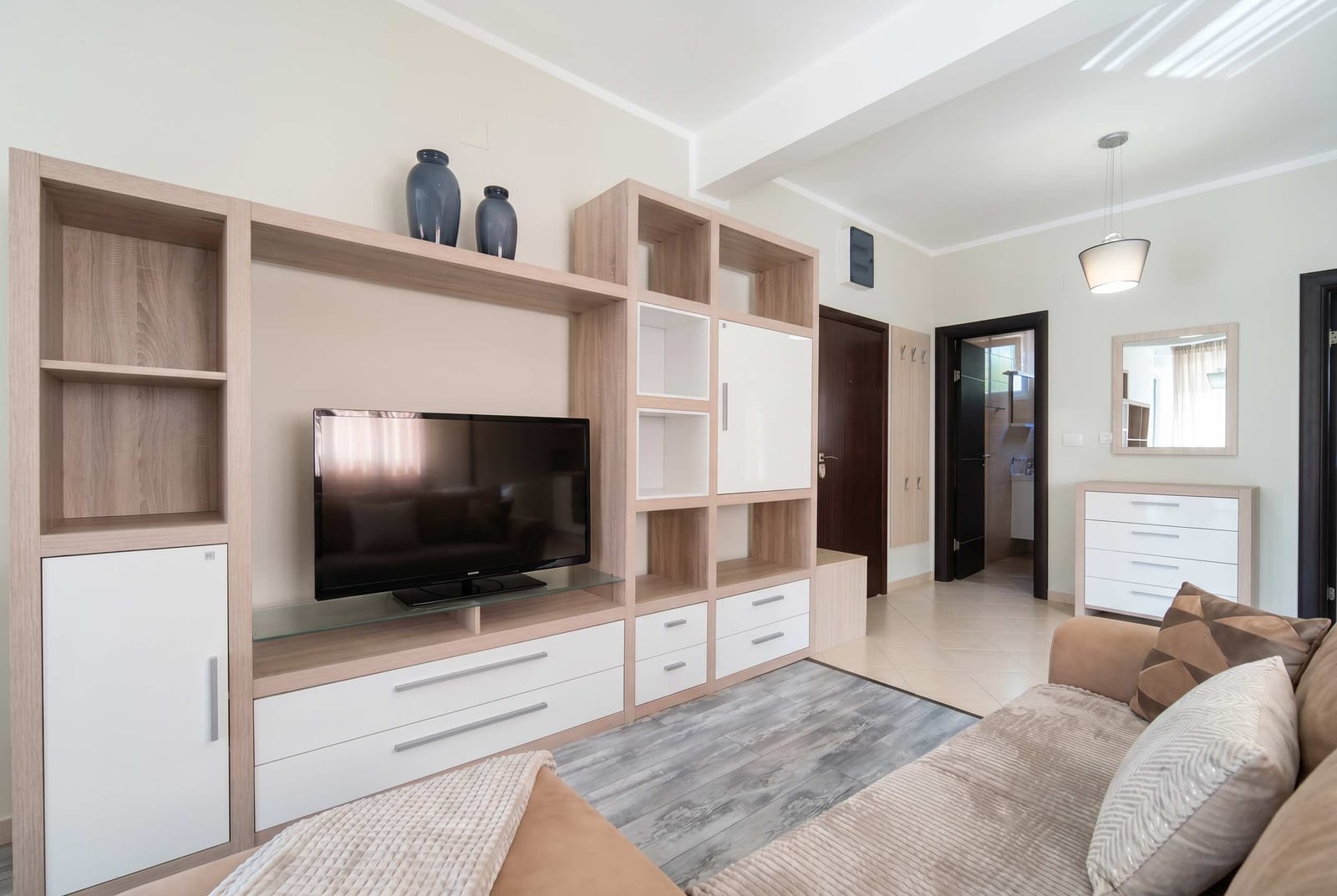 Modern living room with light wood furniture in an apartment in Bečići, Montenegro: TV area, sofa, and bright interior.