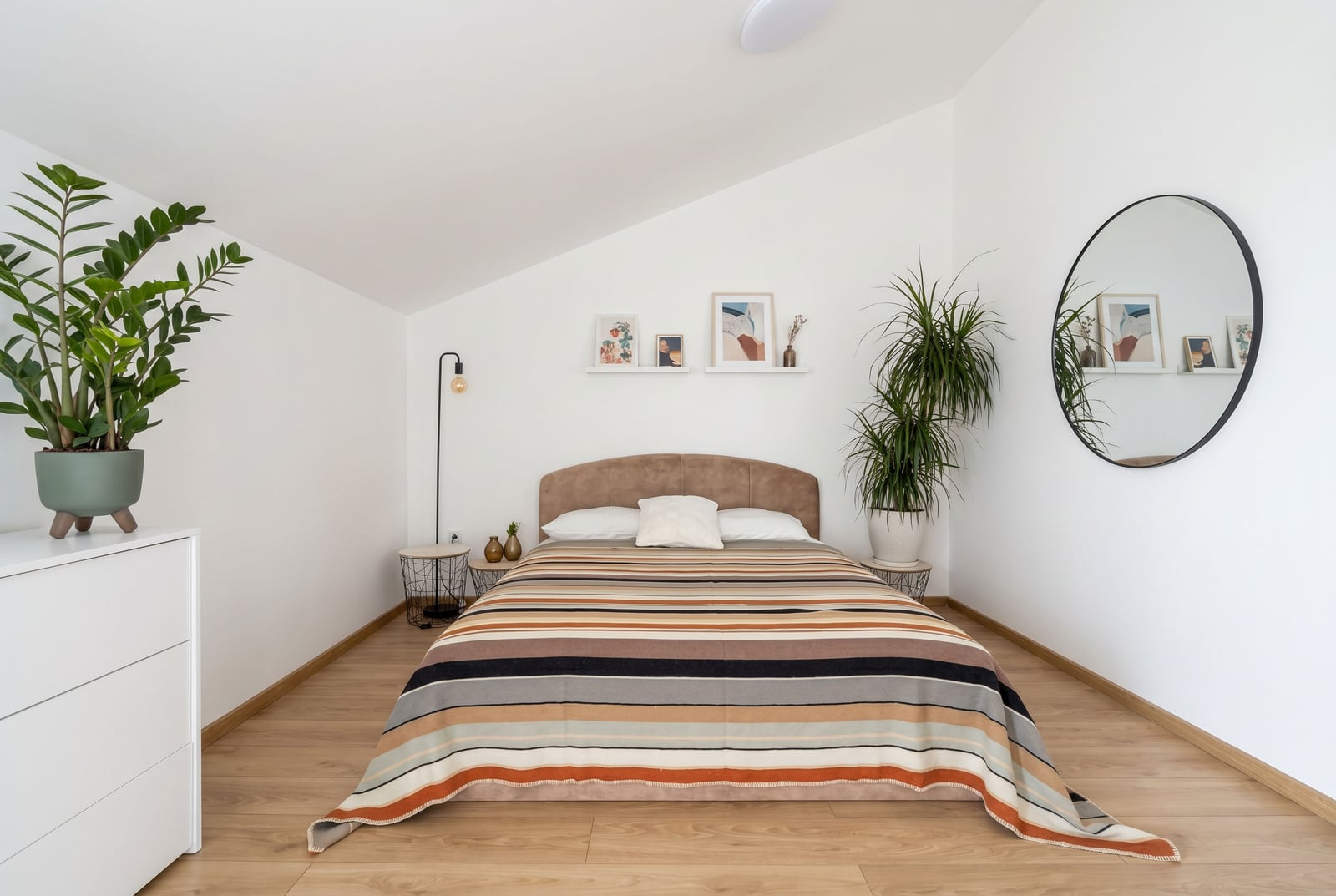 Cozy bedroom in an apartment in Budva, Montenegro: double bed, modern decor, mirror, and houseplants.