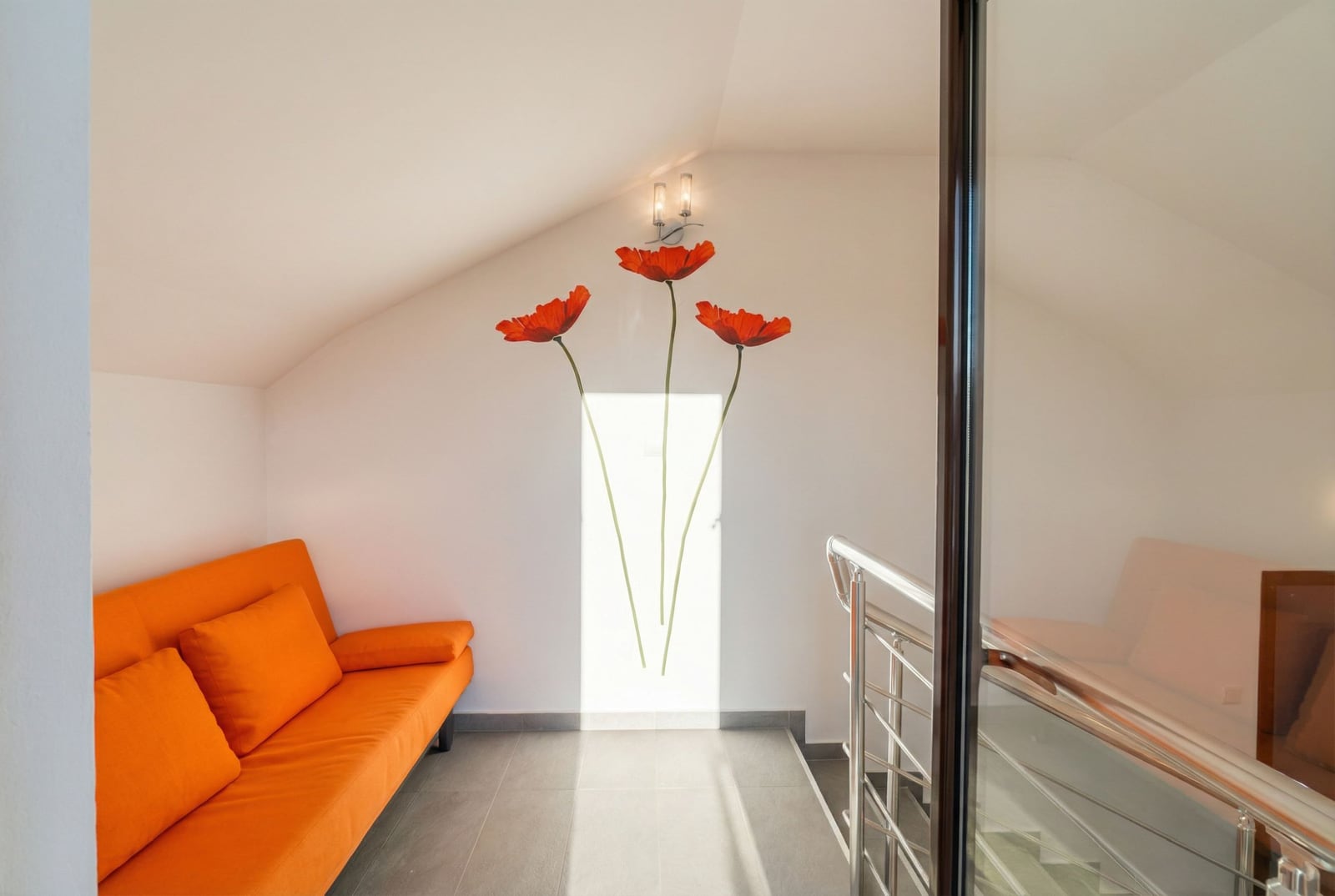 Living room with an orange sofa and poppy-themed decor in an apartment in Bečići, Montenegro. Attic floor with a staircase.