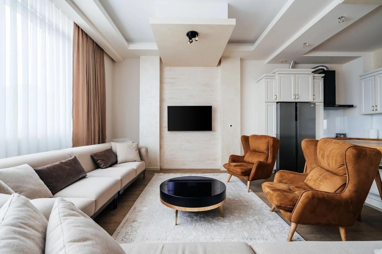 Modern living room with a beige sofa and brown armchairs in an apartment, Budva, Montenegro. Interior with TV area.