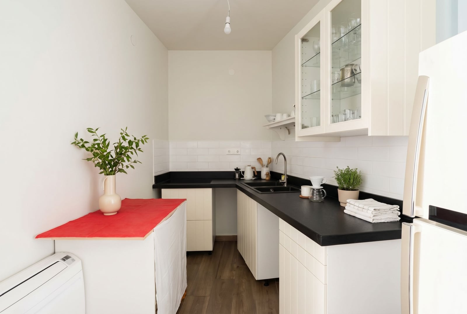 Bright kitchen in an apartment in Budva, Montenegro: white cabinets, black countertop, subway tile backsplash.