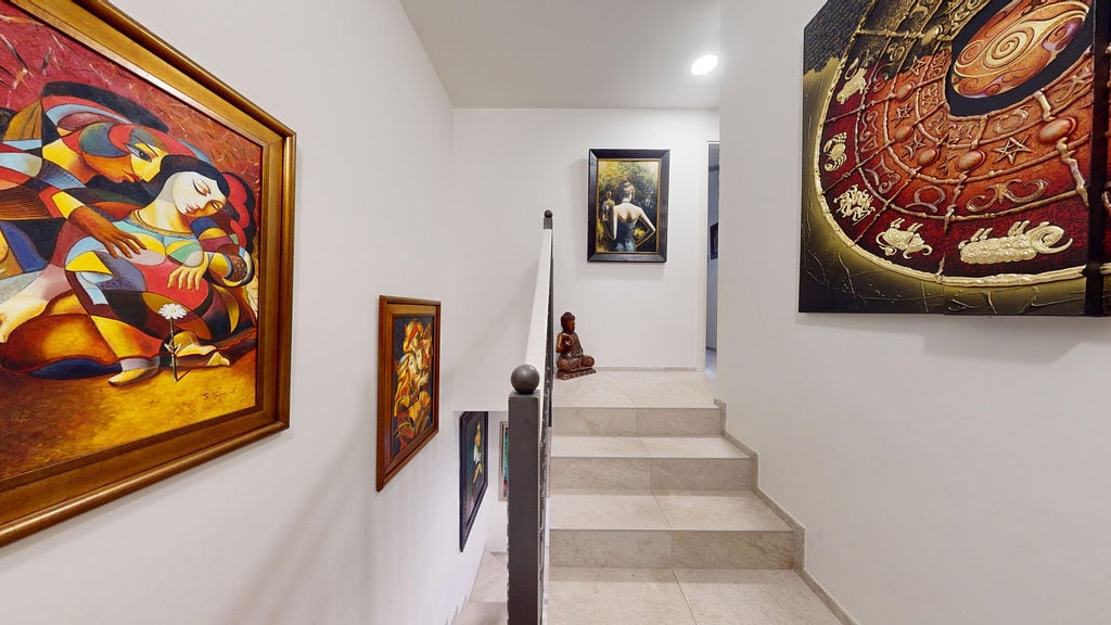Bright staircase in a townhouse at Luštica Bay, Montenegro: walls with paintings, tiled finishes, and a Buddha figurine.