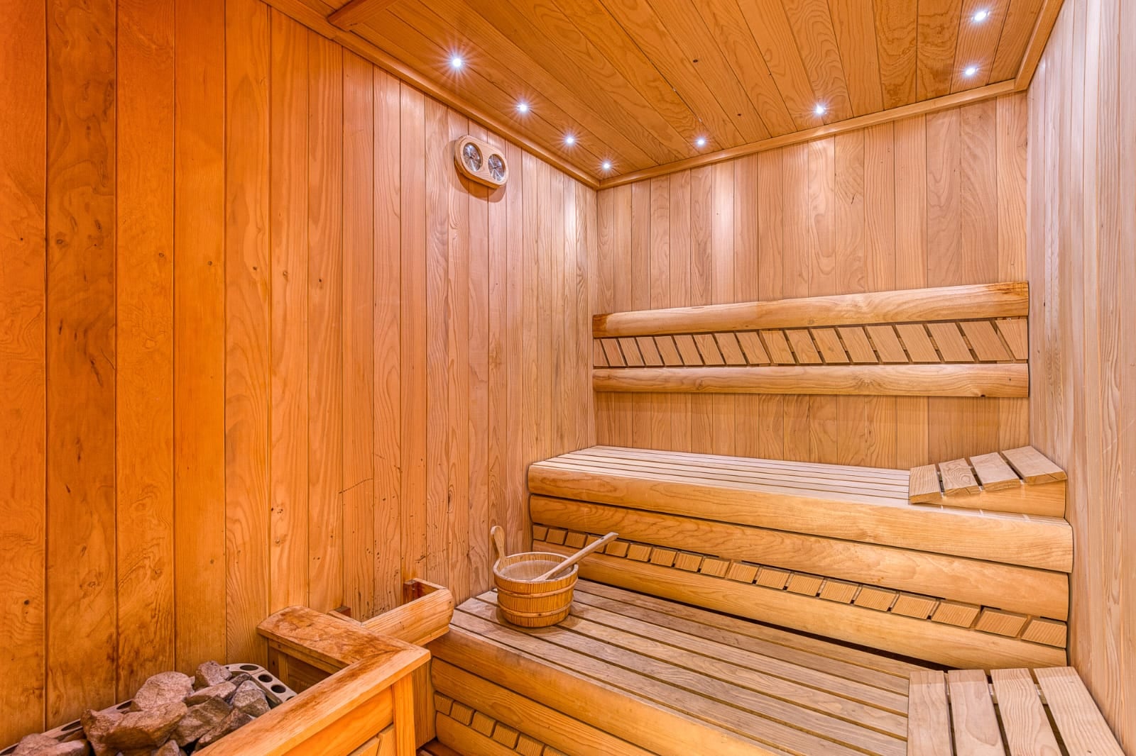 Modern wooden sauna with ambient lighting in a villa in Bečići, Montenegro: wood paneling, benches, and sauna heater.