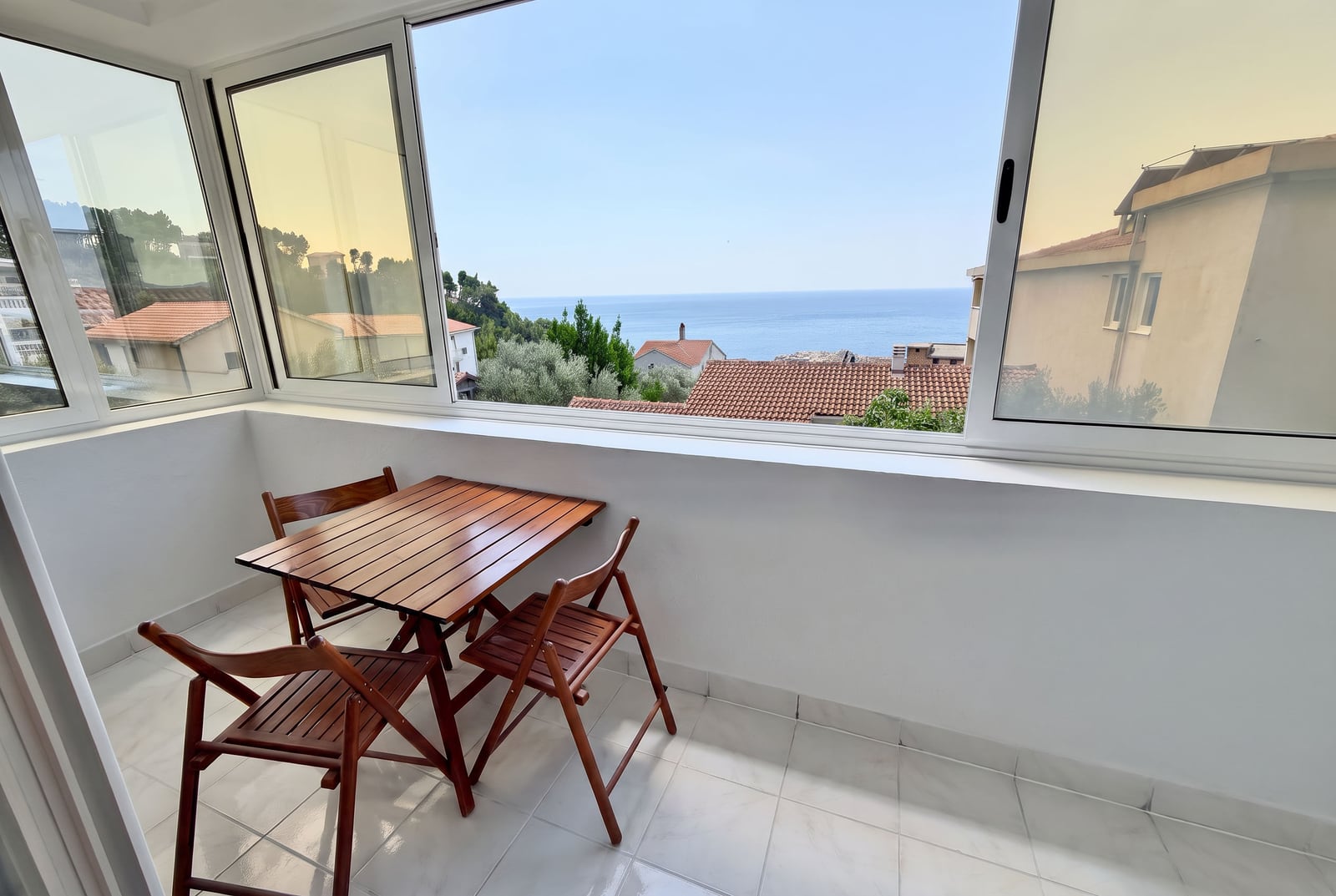 Balcony with wooden furniture and panoramic sea view in an apartment, Sveti Stefan, Montenegro.