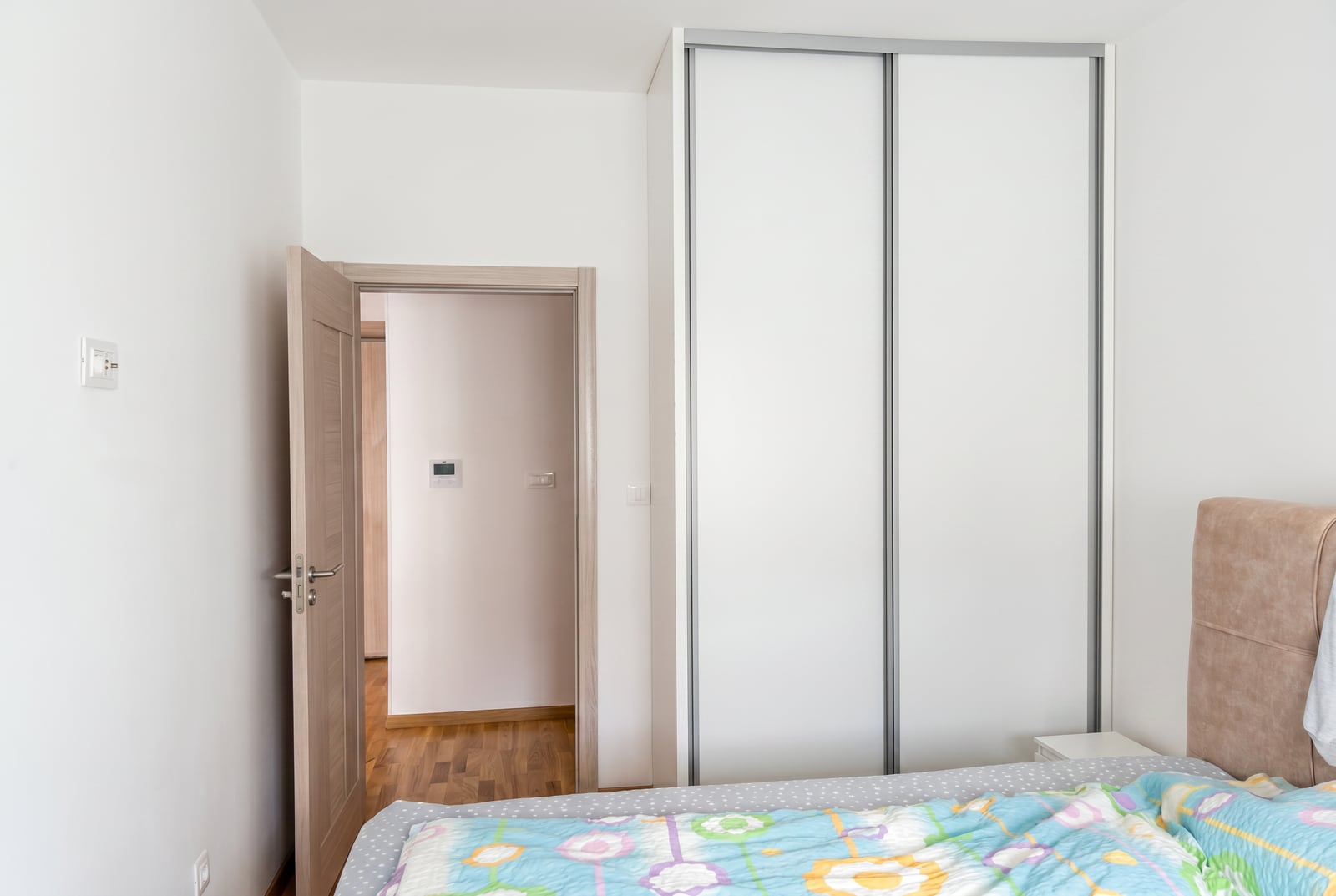 Bedroom in an apartment in Bečići, Montenegro: bright interior, built-in wardrobe, and access to a hallway with parquet flooring.