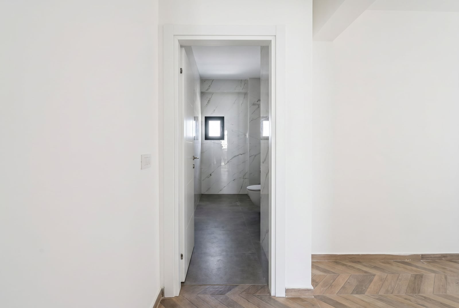 Modern marble-finished bathroom in a new apartment in Budva, Montenegro, view from a bright room.