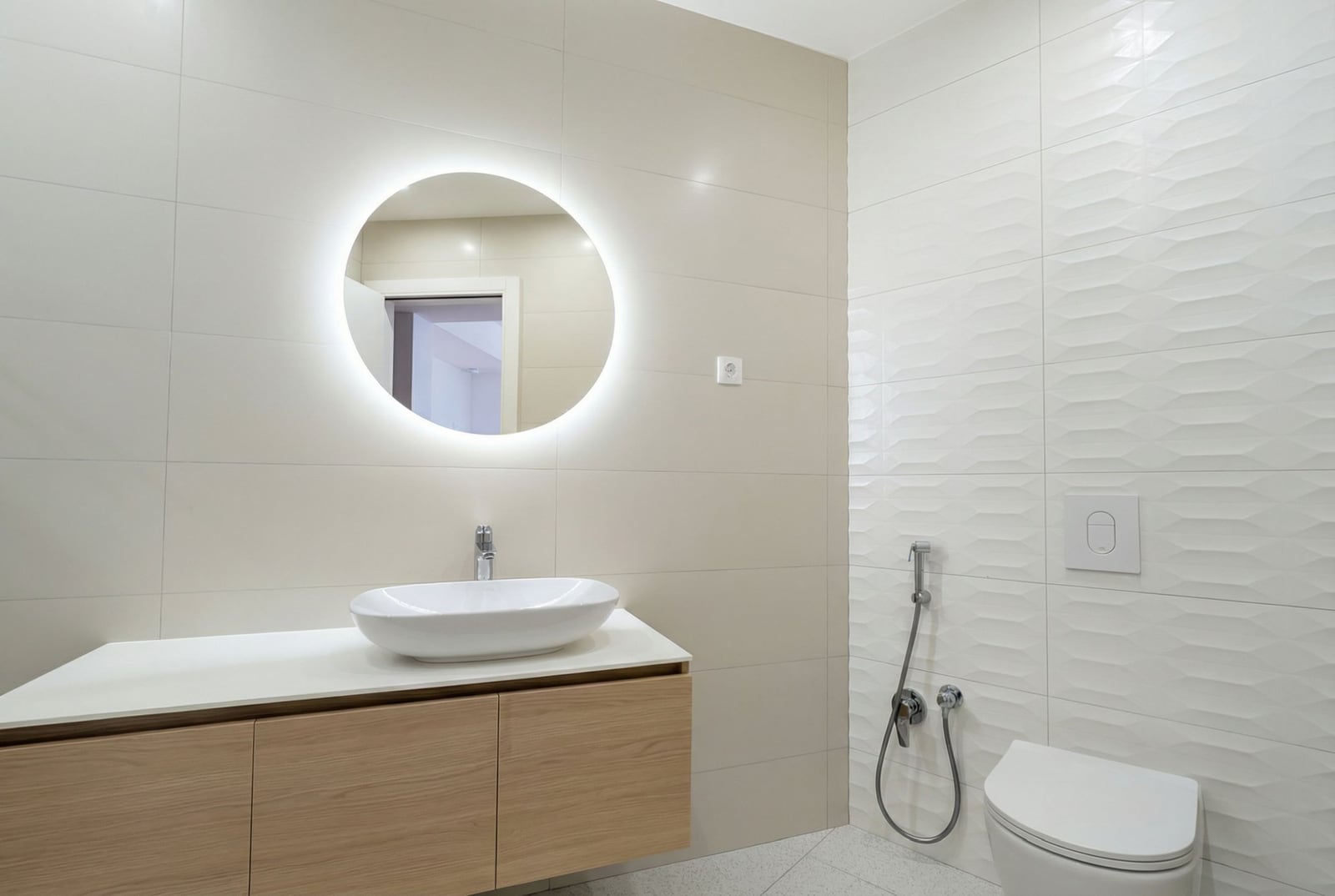 Modern bathroom in an apartment, Bečići, Montenegro: wall-mounted vanity, countertop sink, and backlit mirror.