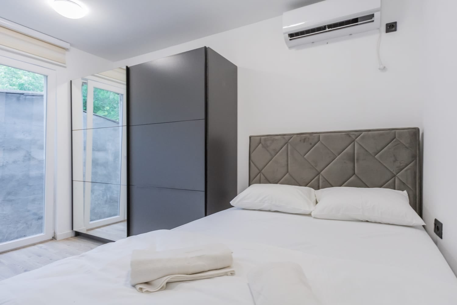 Modern bedroom with a double bed, wardrobe, and air conditioner in a villa in Budva, Montenegro.