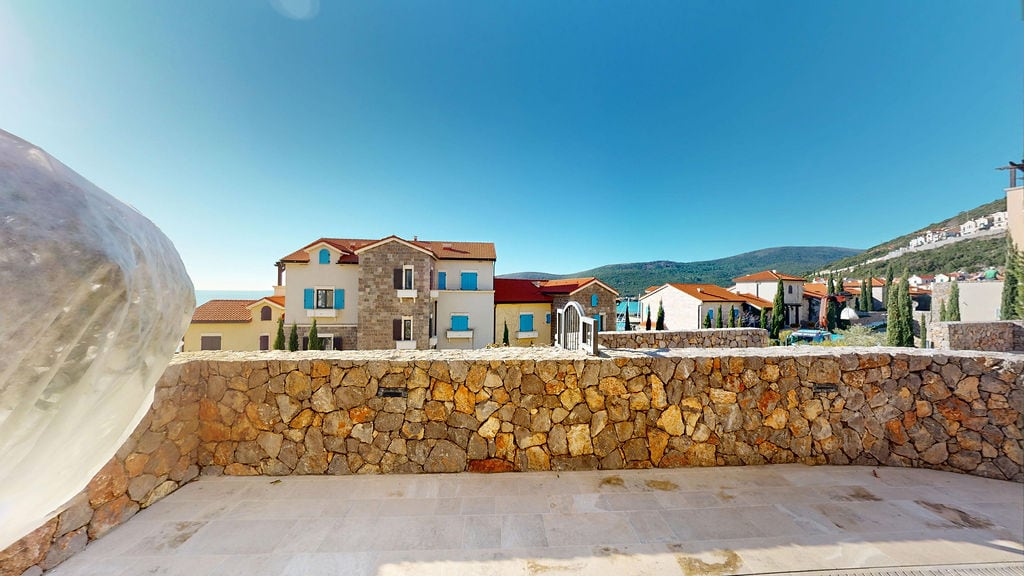 Spacious terrace with stone finish and views of the residential complex and mountains in Luštica, Montenegro.