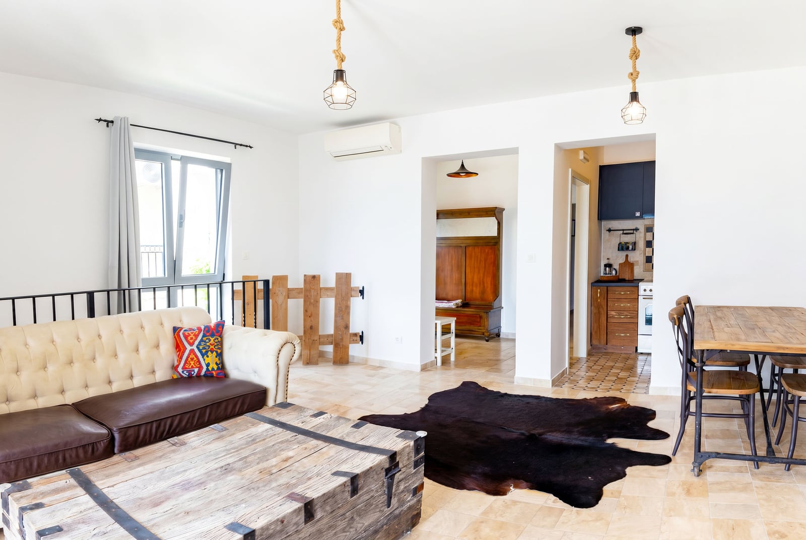 Living room in an apartment in Risan, Montenegro: leather sofa, wooden chest table, dining area, and kitchen.