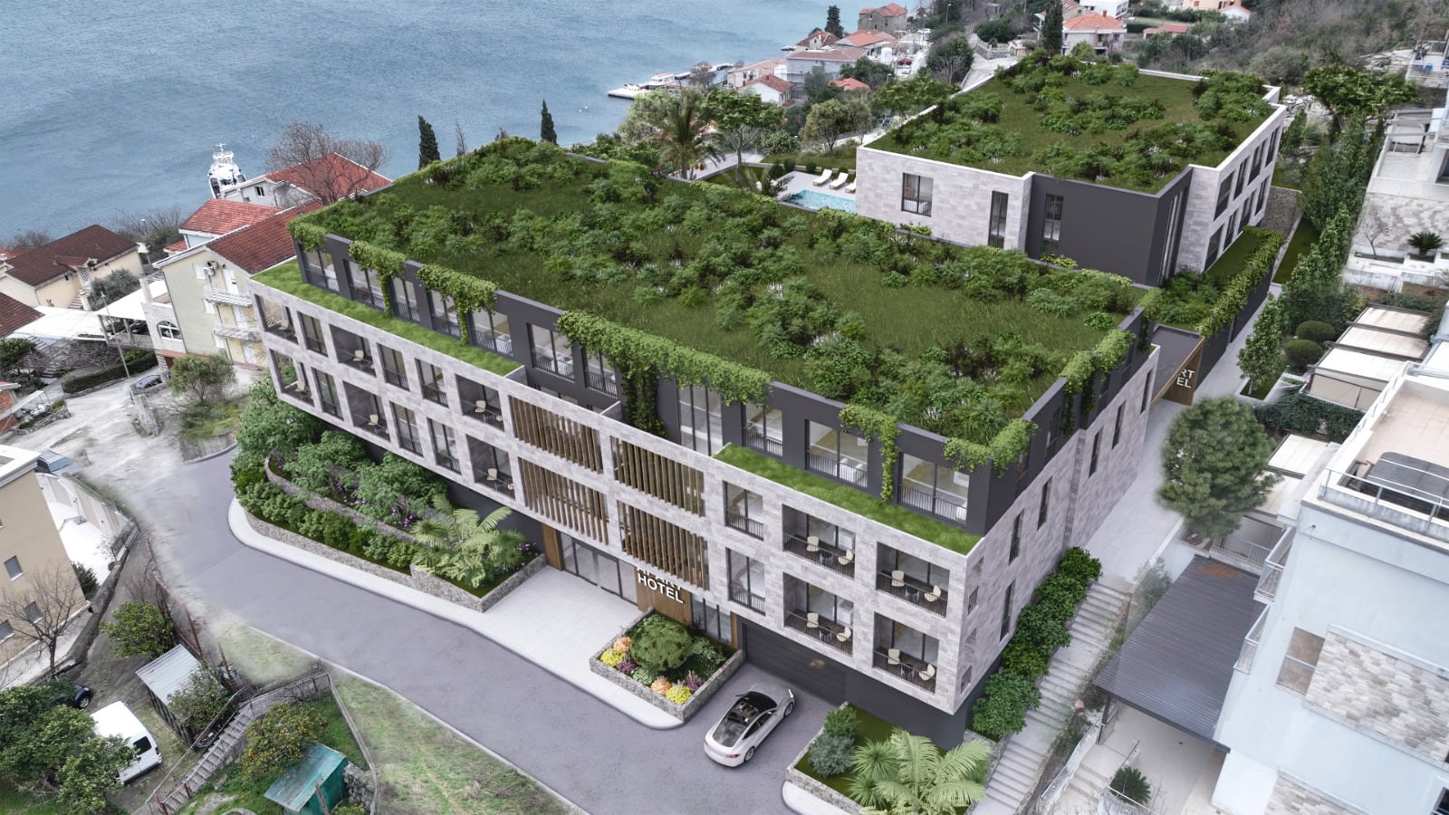 Aerial view of a hotel with a green roof and balconies near the sea.