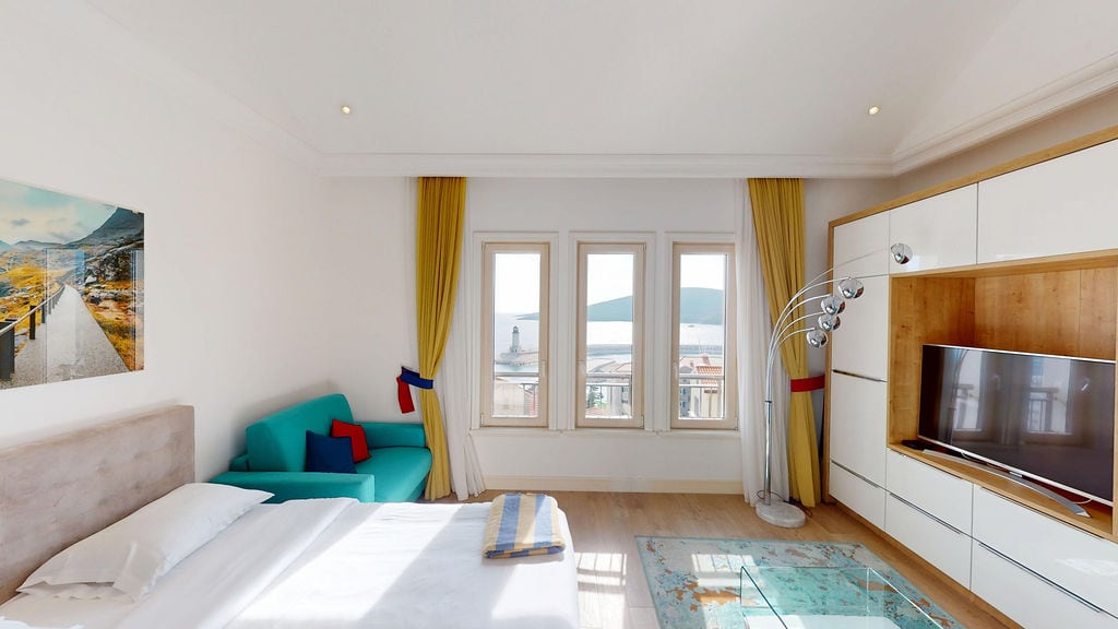 Bright bedroom in Luštica, Montenegro: double bed, turquoise sofa, sea view and lighthouse from the windows.