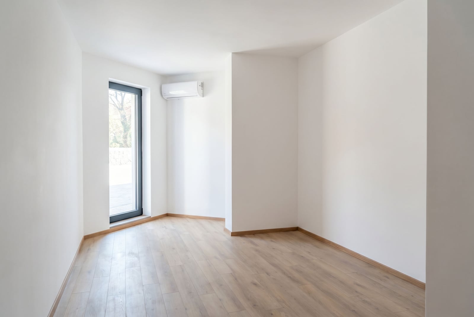 Bright empty living room with laminate flooring and air conditioning in an apartment in Pržno, Montenegro. View of the terrace through the window.