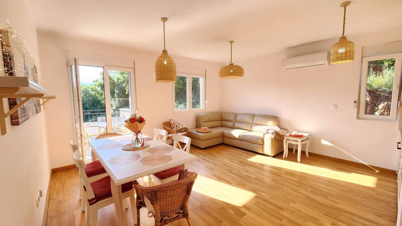 Bright living room with a dining area and balcony access in an apartment, Budva, Montenegro: leather sofa and wicker decor.