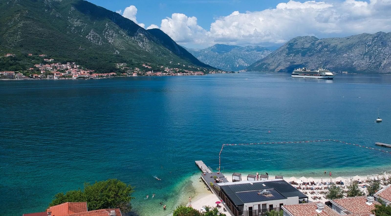 Panoramic view of Kotor Bay and the beach from the villa terrace in Dobrota, Montenegro: sea, mountains, and a cruise ship.