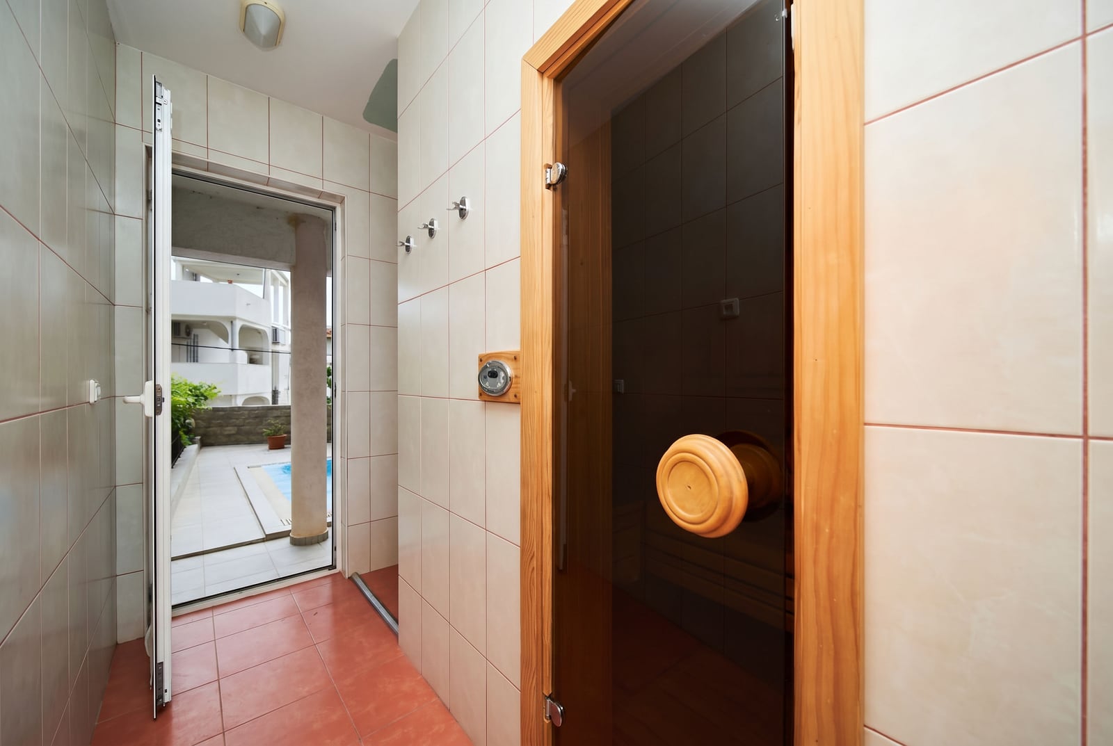 Bathroom with a sauna and pool access in a villa in Bečići, Montenegro. Tiled finish and wooden door.