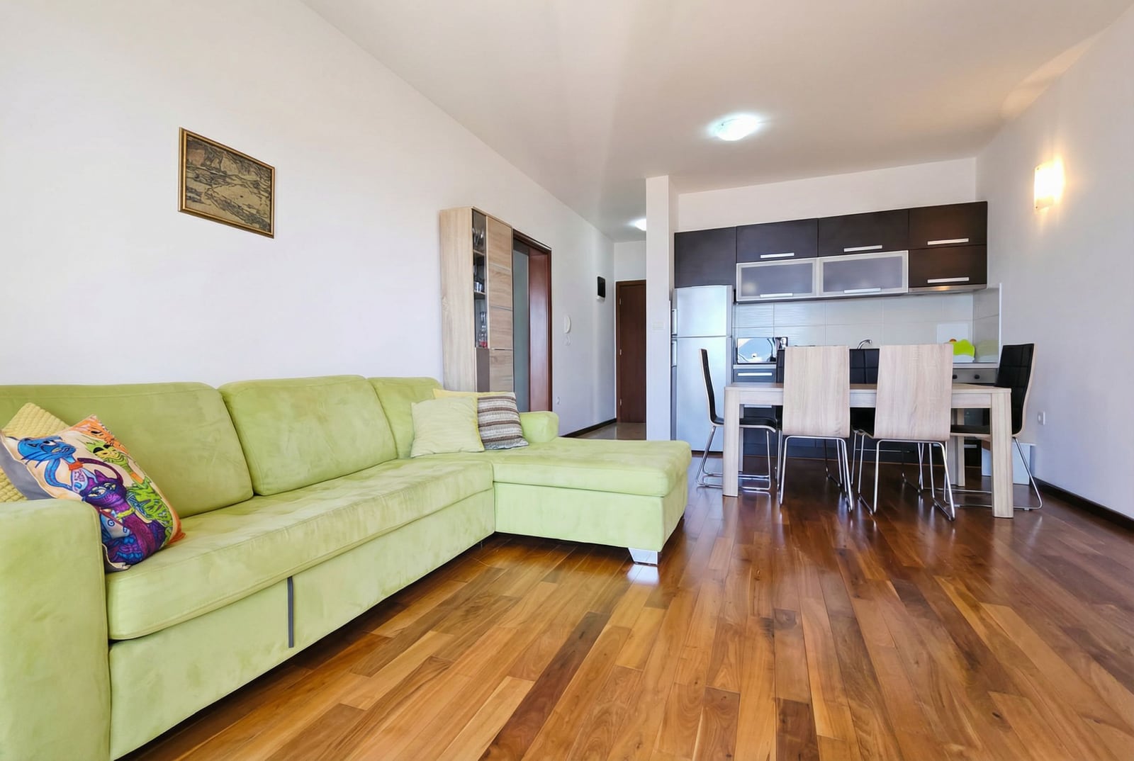Living room with a green corner sofa and dining area in an apartment in Tivat, Montenegro: modern interior.